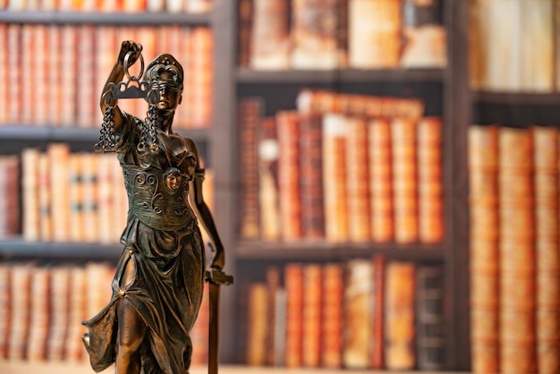 Lawyer office Statue of Justice with scales closeup against the backdrop of a wall of books or a library Legal law advice and justice concept