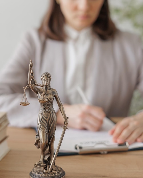 lawyer woman in a light jacket works in an office a statuette of themis the goddess of justice