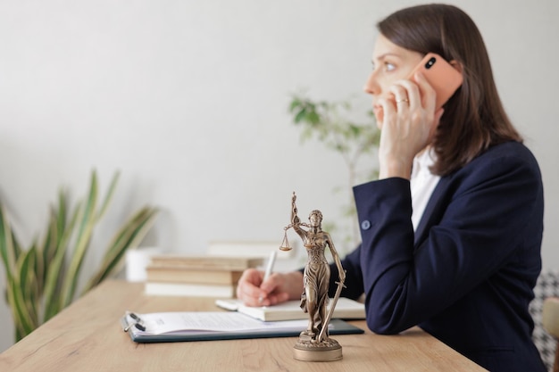 lawyer woman in a light jacket works in an office a statuette of themis the goddess of justice