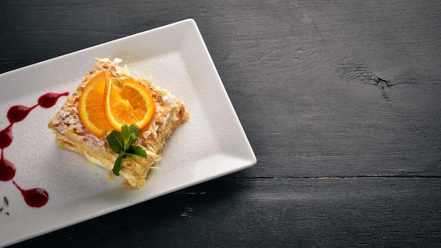 Layered cake with orange flavor. On a wooden background. Free space for your text. Top view.