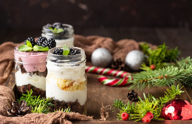 Layered desserts with cake, whipped cream and blackberries on christmas background