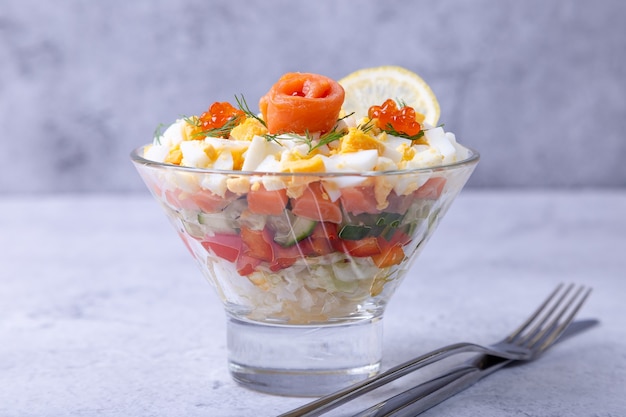 Layered salad with salted trout, caviar, eggs and vegetables