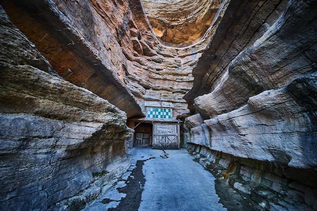 Layers of cliffs through canyon with paved path leading to cave entrance