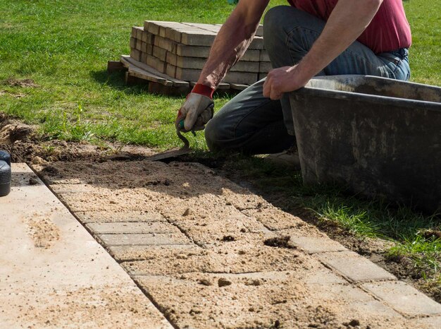 Laying gray concrete paving slabs in house courtyard driveway patio Professional worker