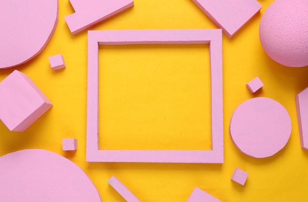 Layout composition of pink geometric shapes and empty frame for copy space on yellow background Flat lay