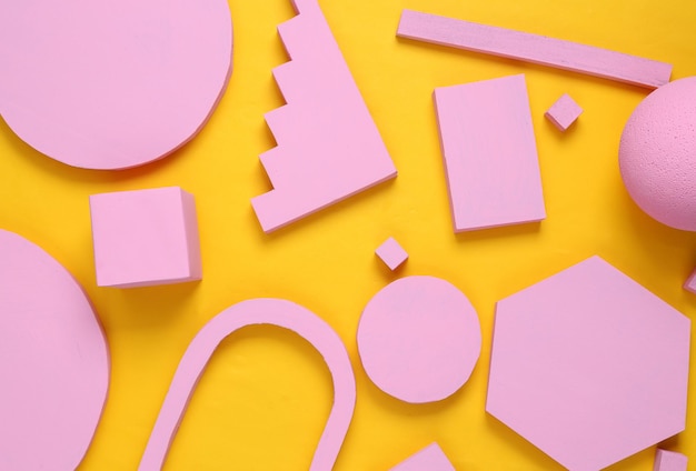 Layout composition of pink geometric shapes on yellow background Flat lay