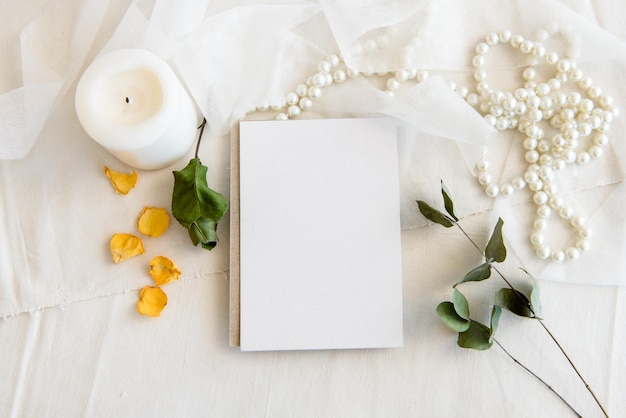 Layout scene of a stationery layout An empty vertical greeting card a string of pearls and dried flowers isolated on a white table background Top view blank for invitation