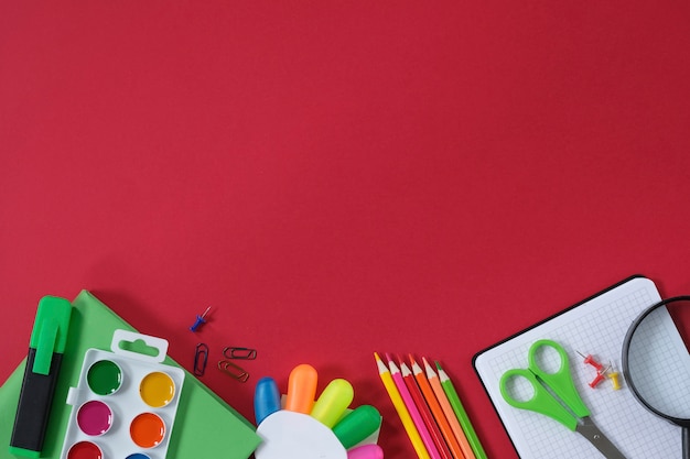 Layout with school supplies and stationery on red background. 