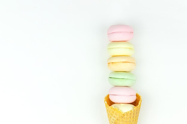 Layout with waffle cone cornet and colored marshmallows looks like macaroons on white background