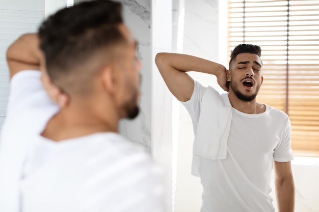 Lazy morning portrait of sleepy young arab man yawning in bathroom