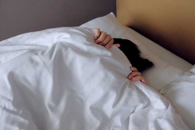 Lazy Young Woman on White Bed in Early Morning