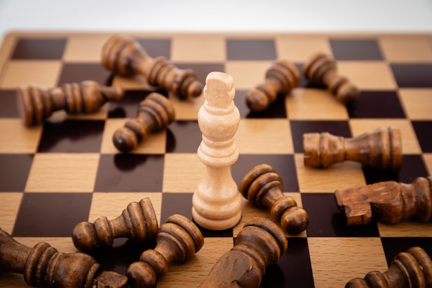 Leader and competition. White Chess King among lying down black pawns on chessboard