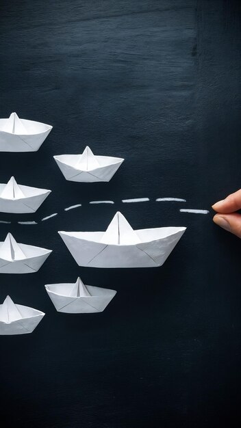 Photo leadership banner concept with paper boat on blackboard background one leader ship leads others