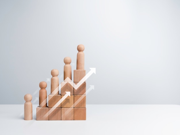 Leadership with business success concept. Modern rising up arrows and wooden figures standing on a growth graph chart steps arranged by wood cube blocks isolated on white background with copy space.