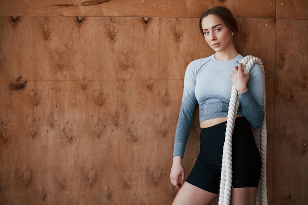 Leaning on the wall. Sportive young woman have fitness day in the gym at morning time