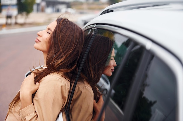 Leans on the door Fashionable beautiful young woman and her modern automobile