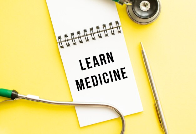 LEARN MEDICINE is written in a notebook on a color table next to pen and a stethoscope Medical concept