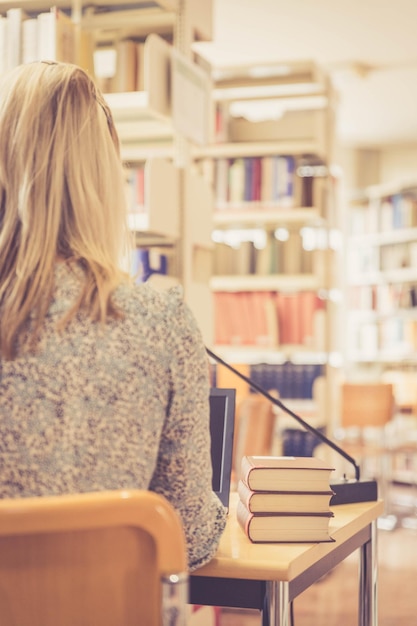 Learning for exams Blonde female student in the university library pile of books