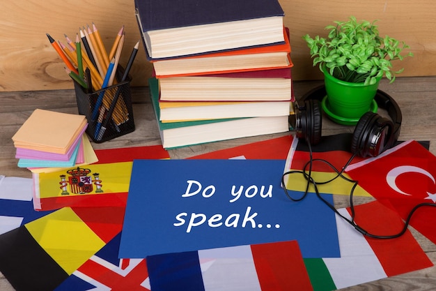 Photo learning languages concept paper with text do you speak flags books headphones pencils on wooden background