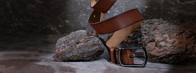 Leather belt on a dark background with bark and natural stone on the background levitation stylish details of men's clothing