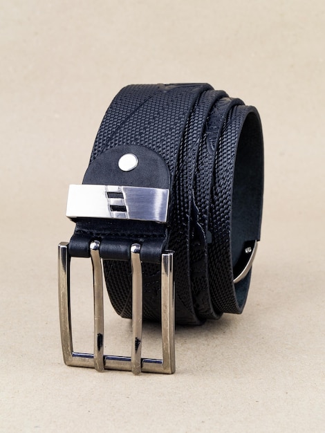 A leather belt with a clasp lies neatly on the table