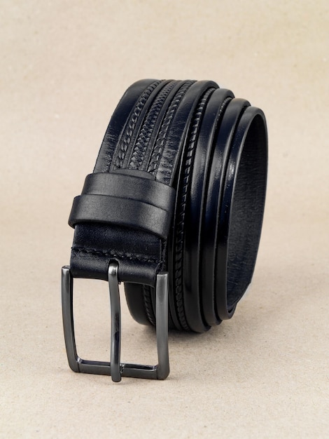 A leather belt with a clasp lies neatly on the table