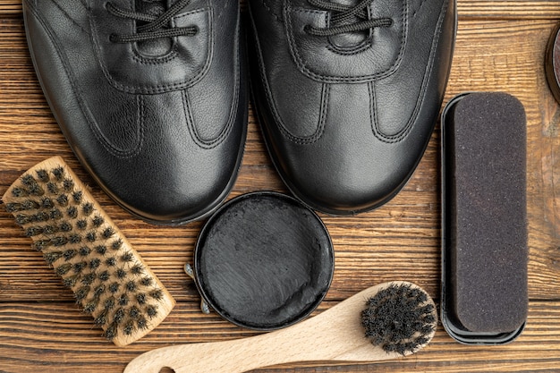 Leather boots, brushes, shoe polish wax, footwear care products on wooden background