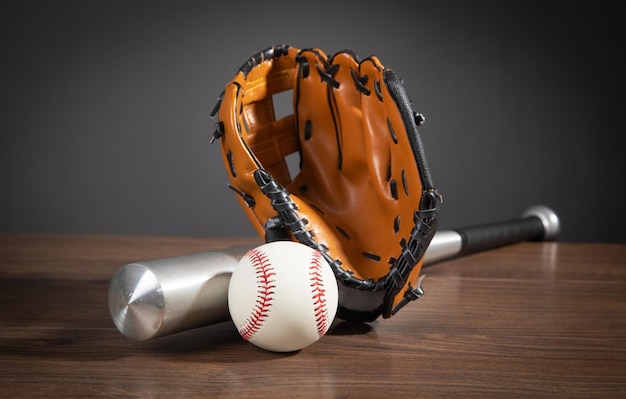 Leather glove with baseball and bat on the wooden background