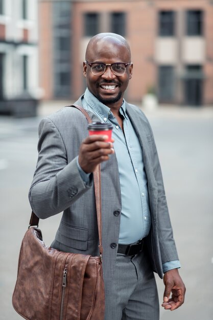 Leather hand bag. Dark-skinned businessman with leather hand bag drinking morning coffee