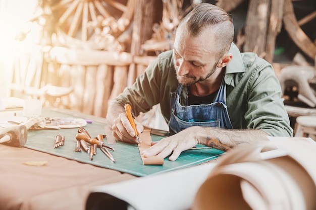 Leather maker artist handcraft working at own workshop small studio made by order masterwork piece