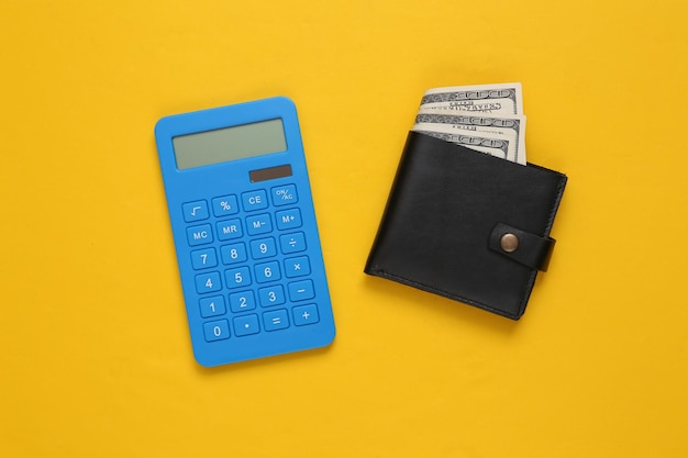 Leather wallet with one hundred dollar bills and calculator on yellow background Saving money