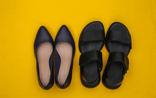 Leather women's sandals and high heel shoes on yellow background. Top view. Flat lay