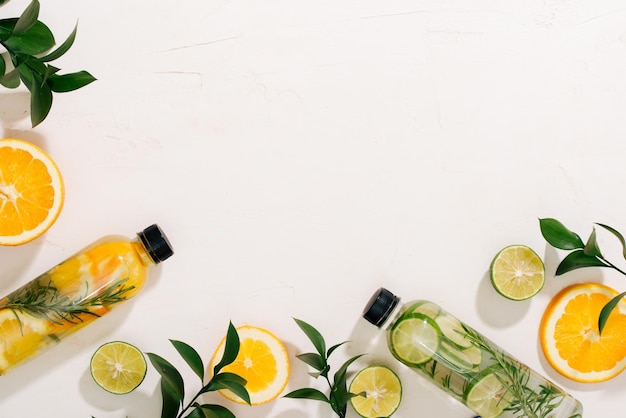 Leaves and bottle tropical water on white background Detox fruit infused water citrus fruits and rosemary leaves Top view flat lay copy space