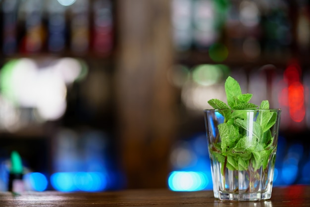 Leaves of fresh mint are in a glass for preparation of a drink on the table 