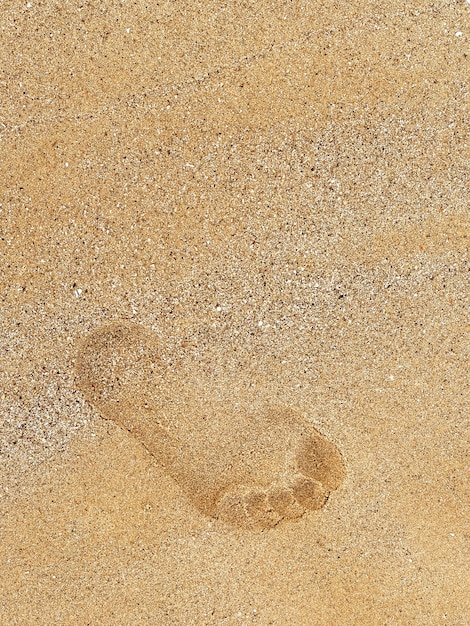 Leaving footprint on the sand Closeup footprint from foot step walking on the sand beach top view with copy space vertical style Beach travel summer background concept