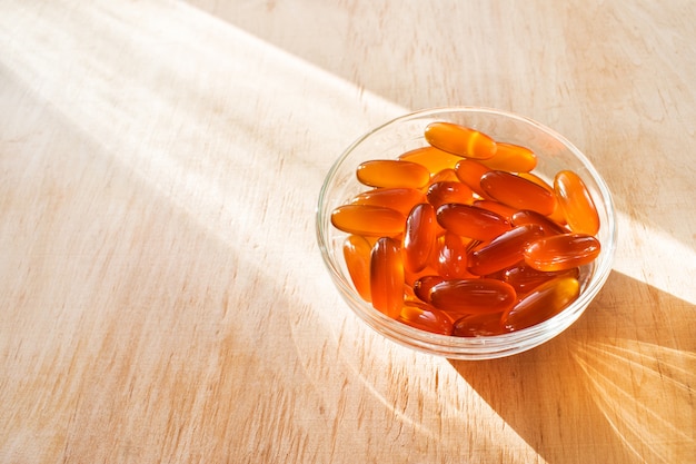 Lecithin gel pills in a round glass bowl with sun light on wooden background