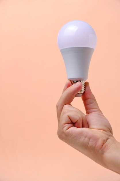 LED eco light bulb in hand on beige background