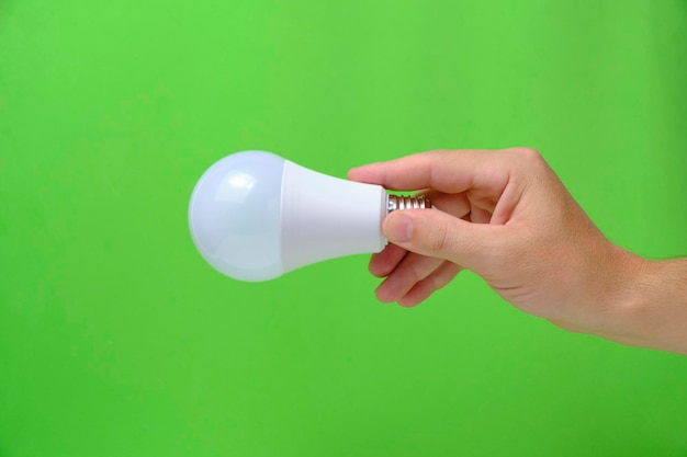 LED eco light bulb in hand on green background