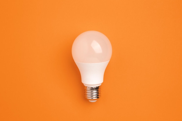 LED lamp on a orange background Energy saving concept alternative energy sources idea