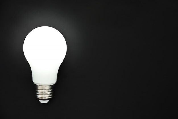 LED light bulb on black background, concept of ideas, creativity, innovation or saving energy, copy space, top view, flat lay