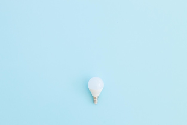 LED light bulb lies on a pastel blue background Energy saving concept Minimalism top view