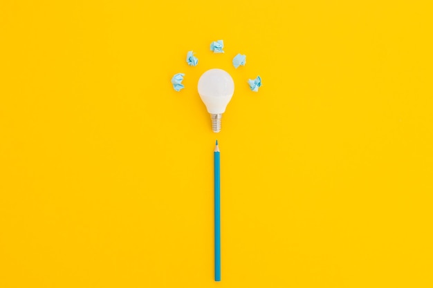 LED light bulb lies on a pastel yellow background Energy saving concept Minimalism top view