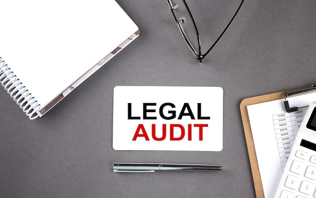 LEGAL AUDIT text written on the card with notebook and clipboard grey background