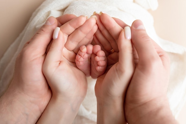 the legs of the child in the arms of the mother and the father the legs of a newborn baby