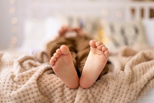 Legs in focus feet of a small child on the bed in beige brown natural tones