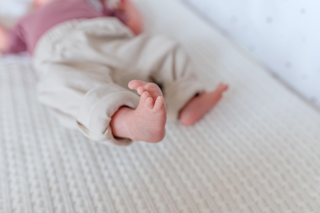 The legs of a newborn baby on a white blanket