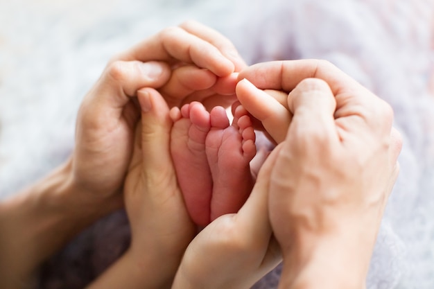 Legs of a newborn in the hands of parents