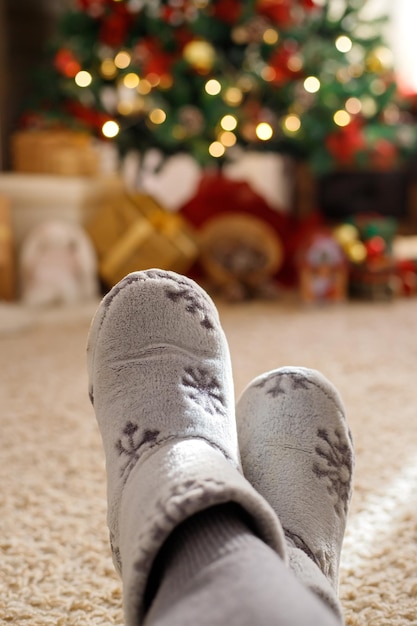 Legs in in a warm home shoes enjoying winter vacation on the background of the xmas tree bokeh lights Christmas time New Year holiday