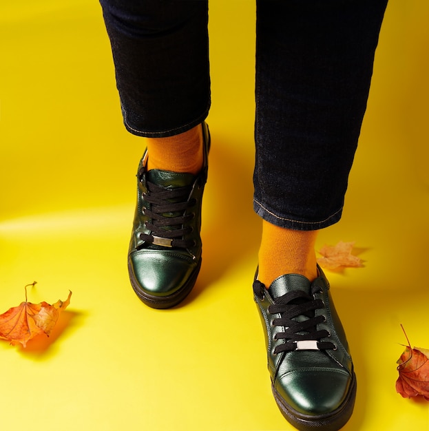 Legs in yellow socks and sneakers on a yellow background