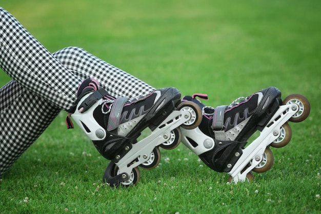 Legs of young roller skater sitting on green grass